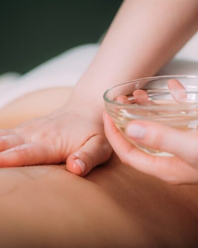 Massaging with massage oil, hands of a female massage therapist massaging a female client