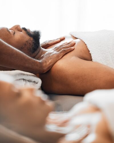 Black man, spa and couple massage for relax, skincare and wellness at resort on anniversary weekend